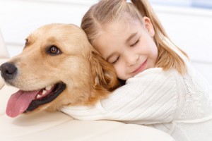 Cute little girl hugging golden retriever with love eyes closed, smiling.